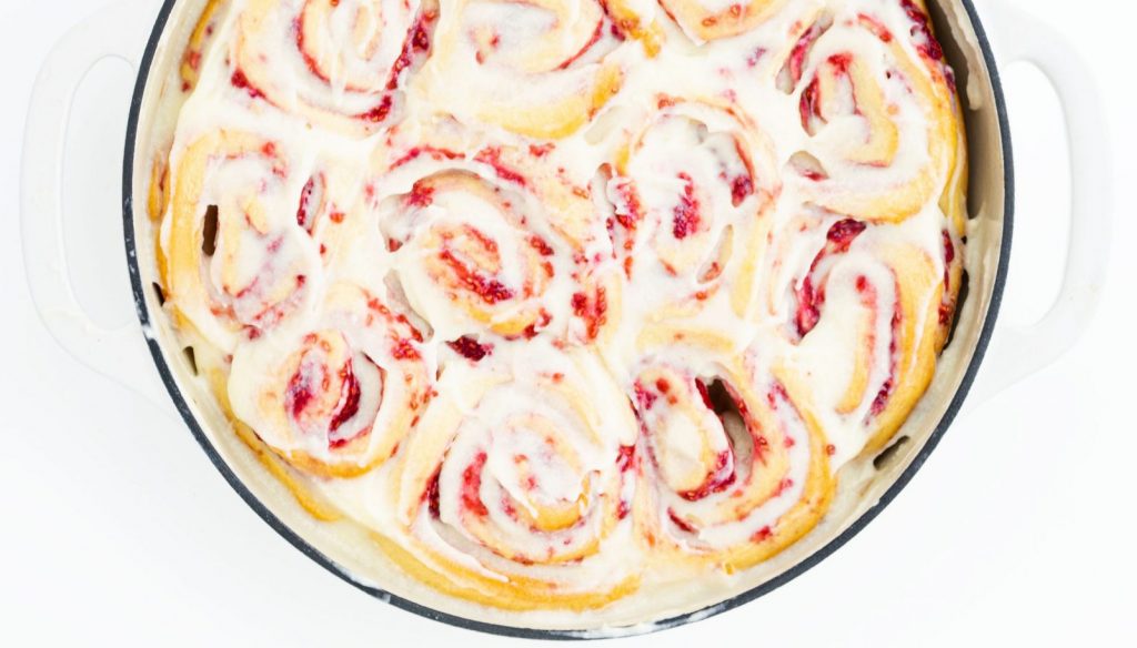 rollos rellenos de mermelada de frambuesa recién horneados con glaseado