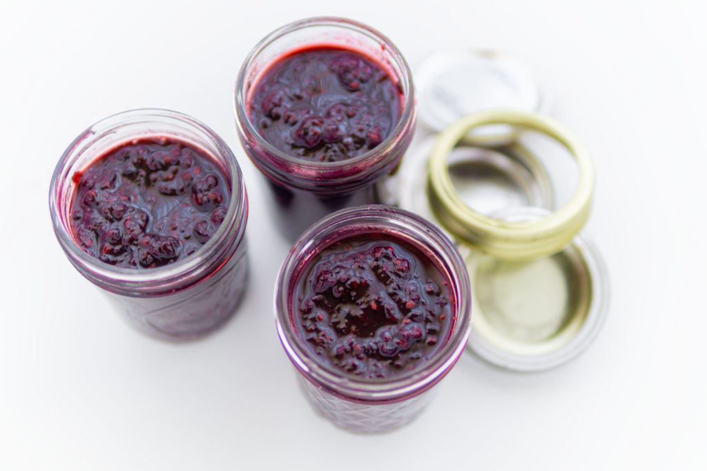 3 tarros de mermelada de mora con tapas al lado