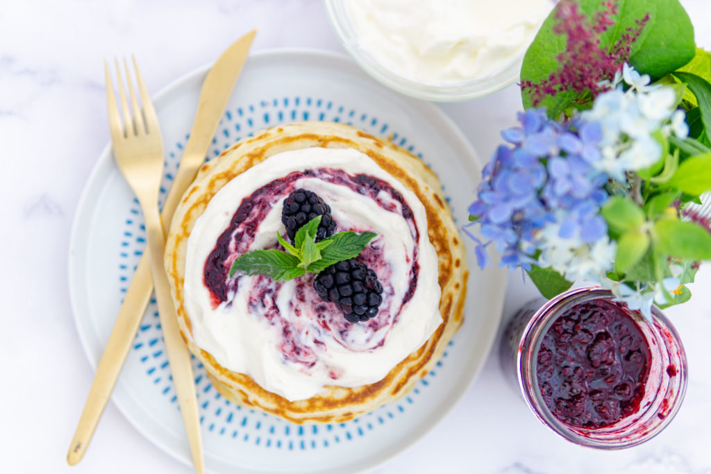 Pancakes con yogur y mermelada de moras casera en pequeños lotes, decorados con moras frescas y hojas de menta