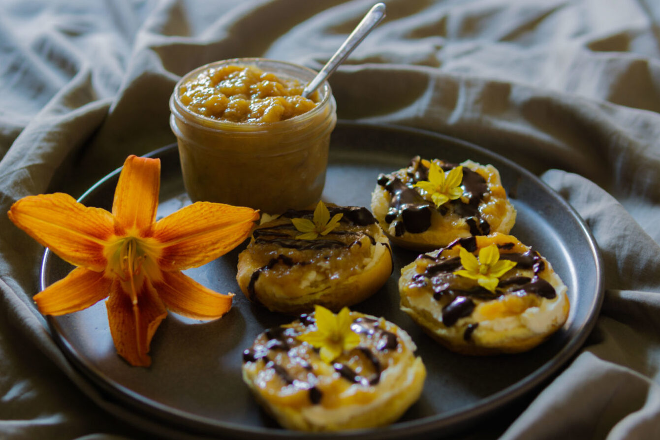 tarro con mermelada de plátano y tostadas con mascarpone y chocolate en una bandeja con flores decoración