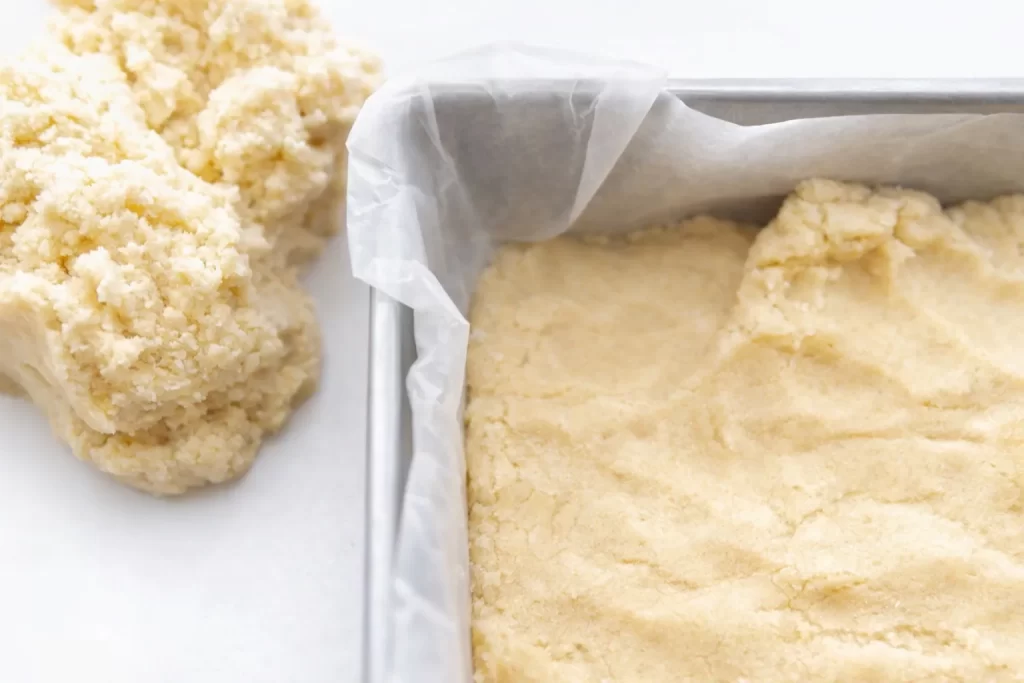 Buttery dough pressed into a baking pan to form the base of blueberry crumb bars